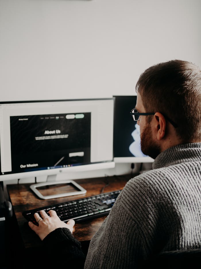 Mastering the First Impression: Your intriguing post title goes here Man working on web design at home office setup with dual monitors.